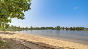 A sandy beach with a calm lake, trees, and a clear sky. - Lake Access, Pools & More: Family Home in Stanwood (Stanwood)