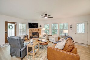 A living room with a fireplace, leather chairs, a sofa, and a television.