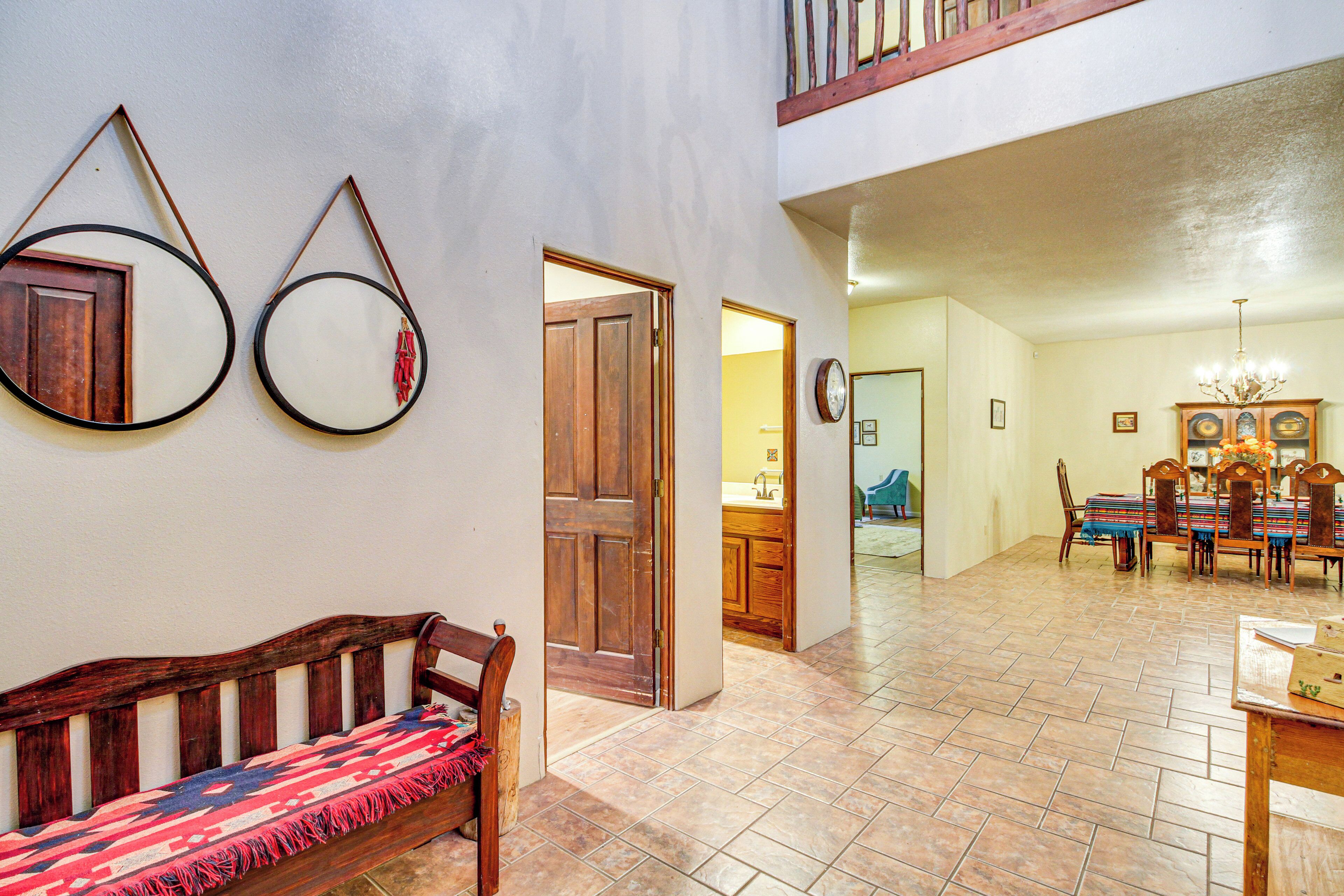 A spacious living area with a wooden bench, a dining table with chairs, and a kitchen in the background.