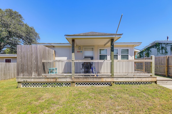 A single-story house with a covered porch, a fenced yard, and a wooden deck.