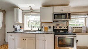 A modern kitchen with white cabinets, stainless steel appliances, and a large window providing natural light. - Charming Apt w/ Shared Outdoor Space in Lisbon! (Lisbon)