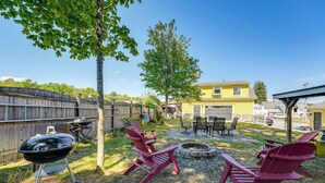 A backyard with a barbecue grill, red Adirondack chairs, a fire pit, and a yellow house in the background. - Charming Apt w/ Shared Outdoor Space in Lisbon! (Lisbon)