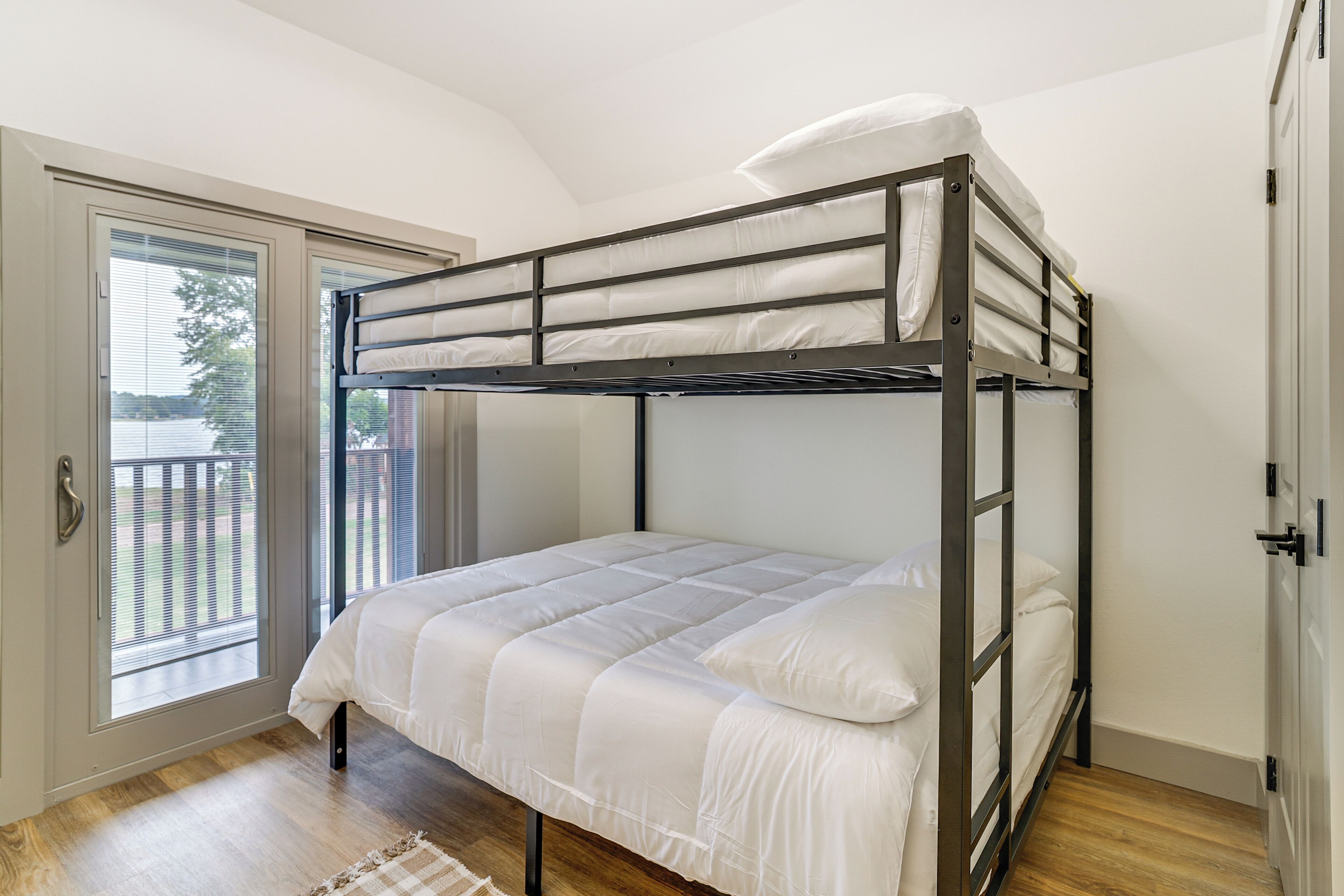 A bunk bed in a room with a sliding glass door leading to an outdoor area.