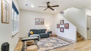 A spacious living room with a sofa, coffee table, and a large rug. A ceiling fan and a staircase are visible in the background. - Lake-view Retreat w/ Games & Yard in Daingerfield (Daingerfield)