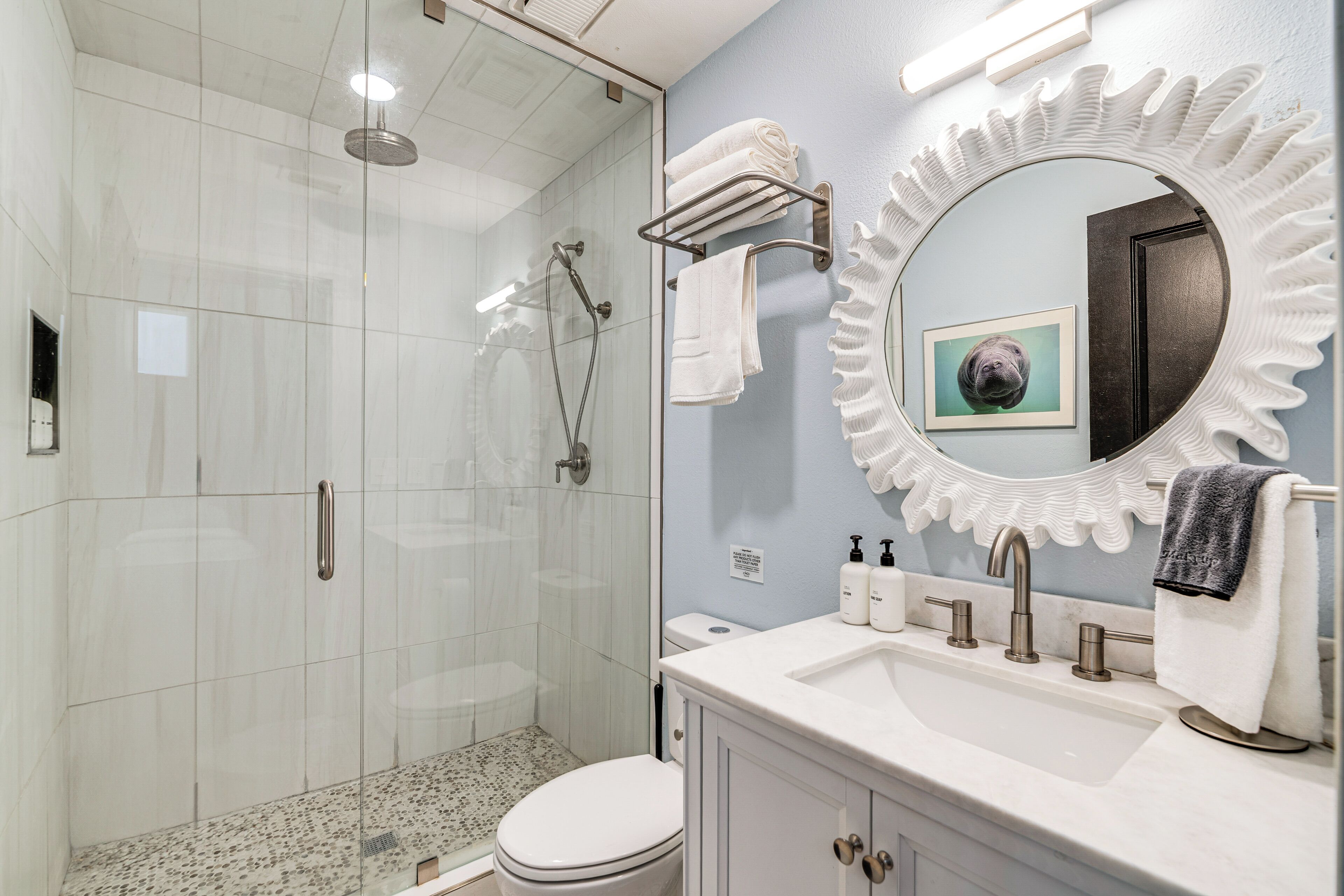 A modern bathroom with a glass-enclosed shower, a white sink with a vanity, and a decorative mirror.