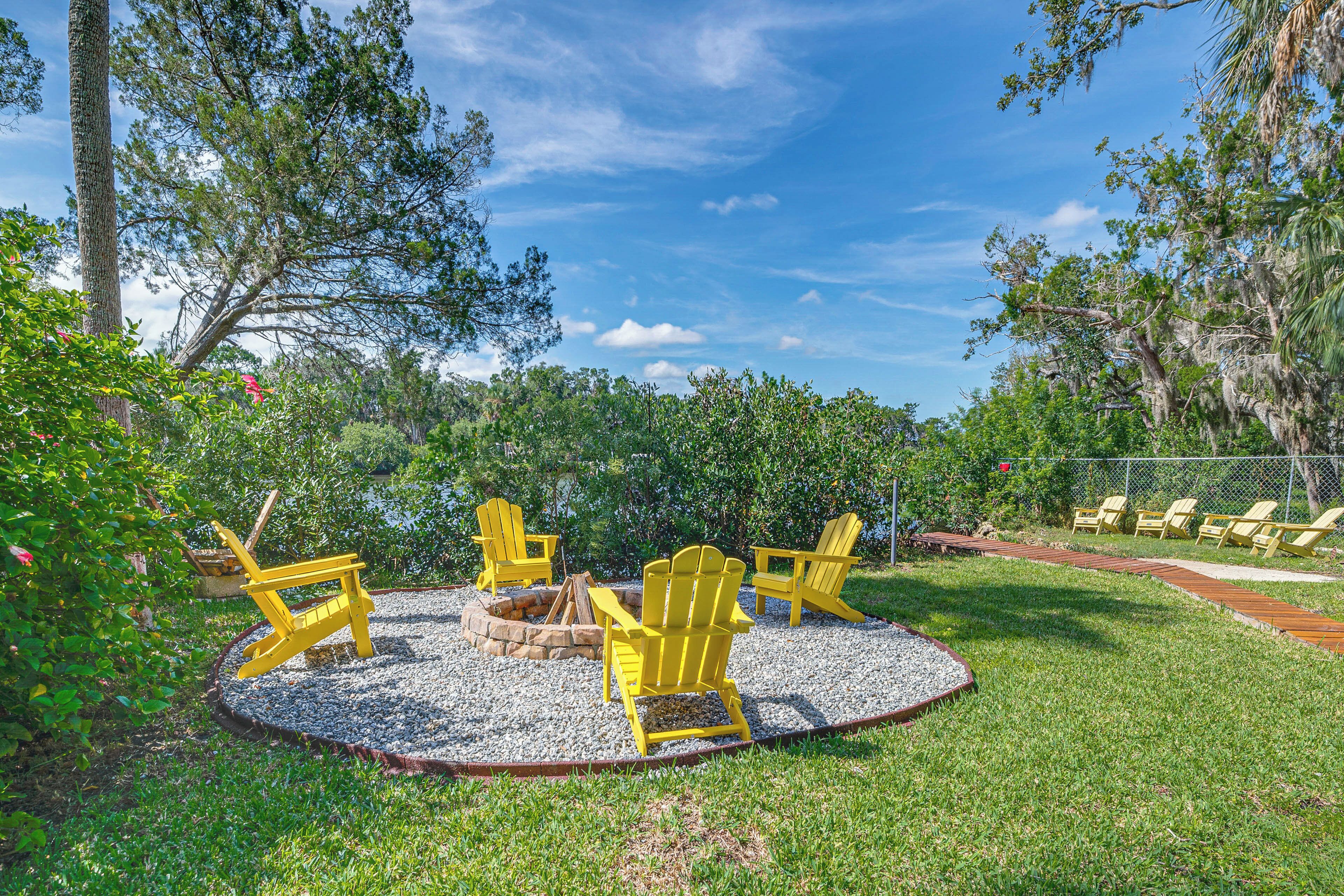 A circular seating area with a fire pit, surrounded by gravel, and yellow Adirondack chairs.