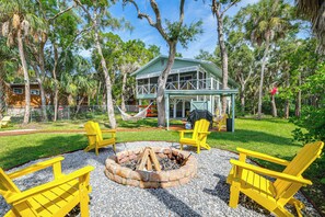 A backyard with a fire pit, yellow Adirondack chairs, and a house with a porch. - Dock, Hot Tub & Games: Crystal River Family Gem (Crystal River)
