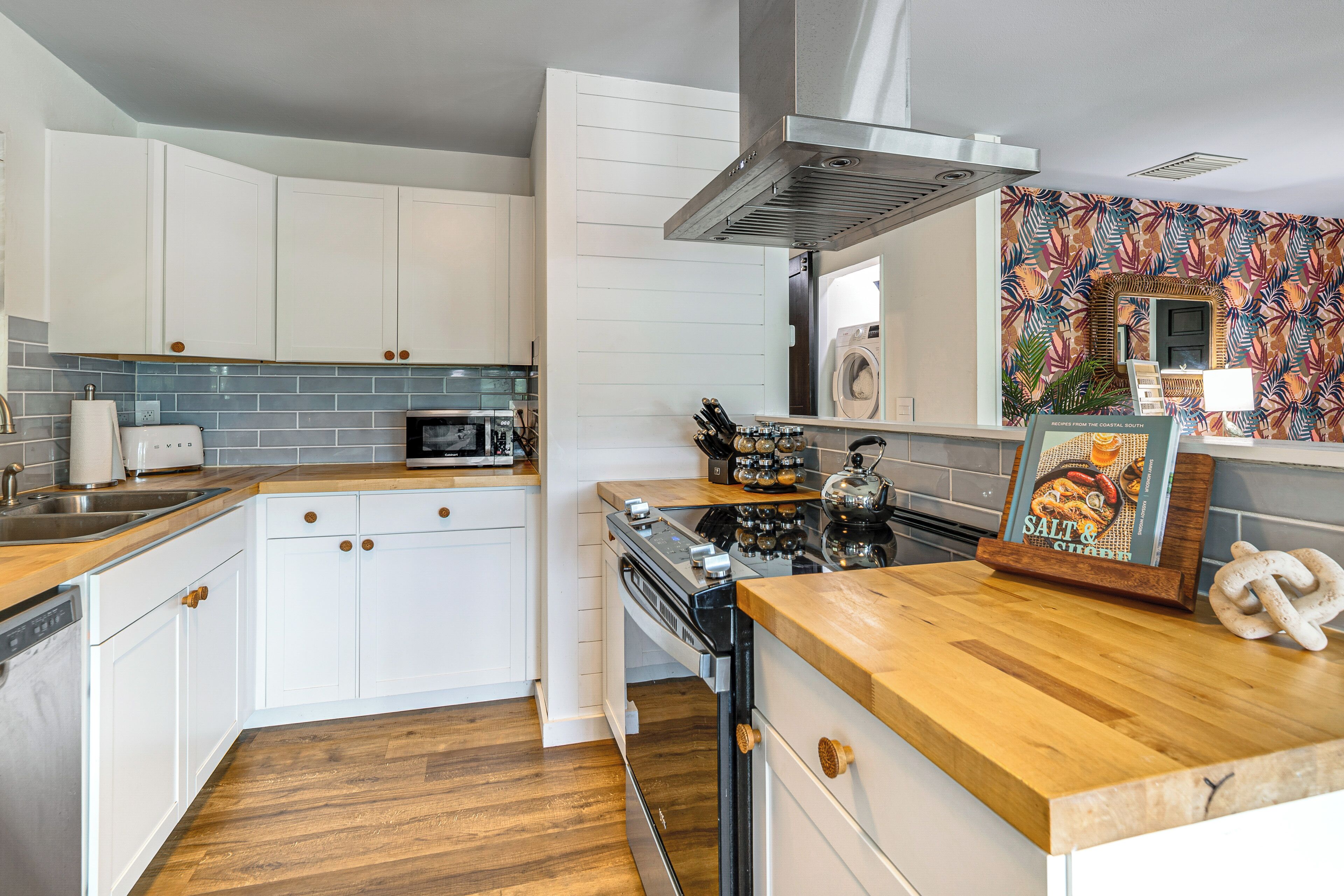 A modern kitchen with white cabinets, a microwave, a stove, and a wooden countertop.