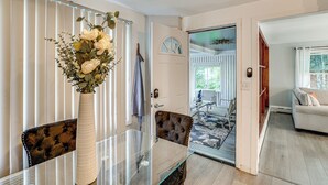 Ein modernes Wohnzimmer mit einem Glastisch, einem gepolsterten Ledersessel und einer weißen Tür, die in einen anderen Raum führt.