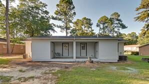 Une maison de plain-pied avec un porche à l’avant, un petit patio et un jardin à l’arrière.