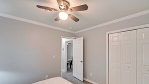 Une chambre dotée d’un ventilateur de plafond, de murs blancs et d’une porte donnant sur une autre pi èce.