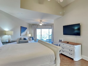 A spacious bedroom with a large bed, a ceiling fan, a flat-screen TV, and a balcony with a view. - Beach Pointe #902 - Ocean Pearl | Near Beach + Pool (Destin)