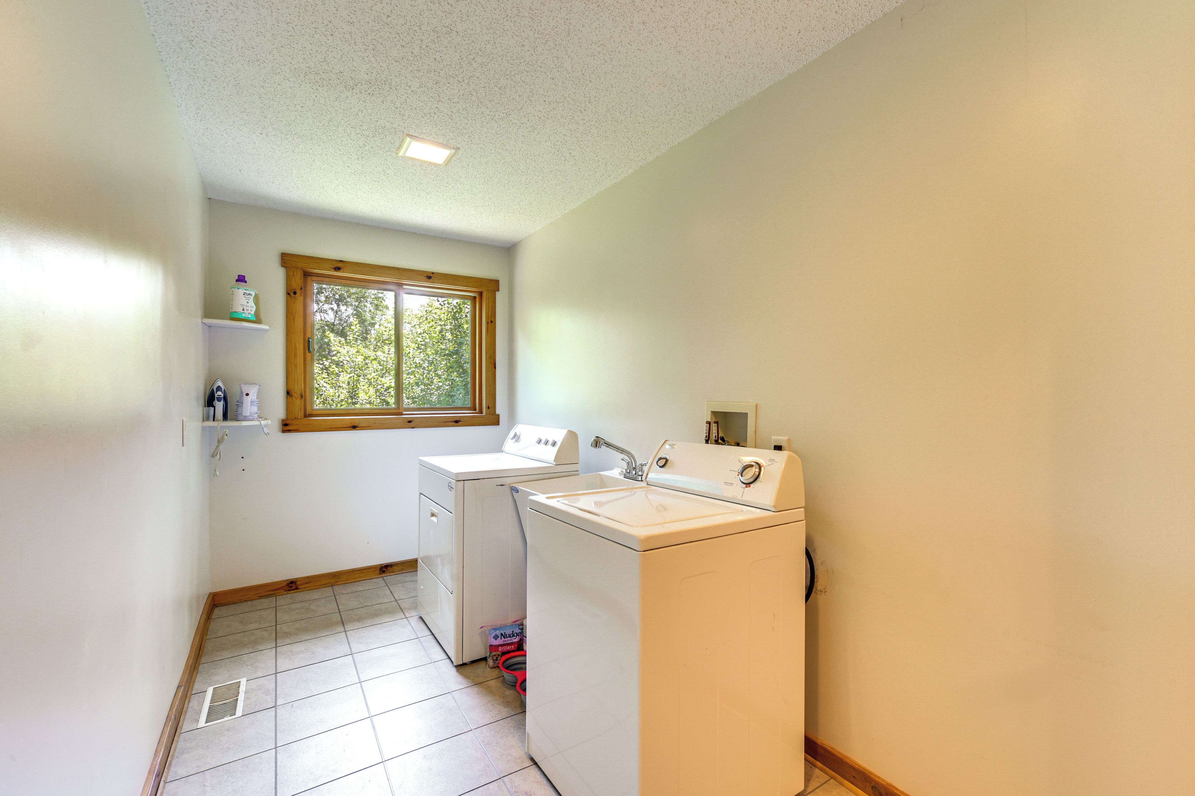 A laundry room with two washing machines, a sink, and a window.