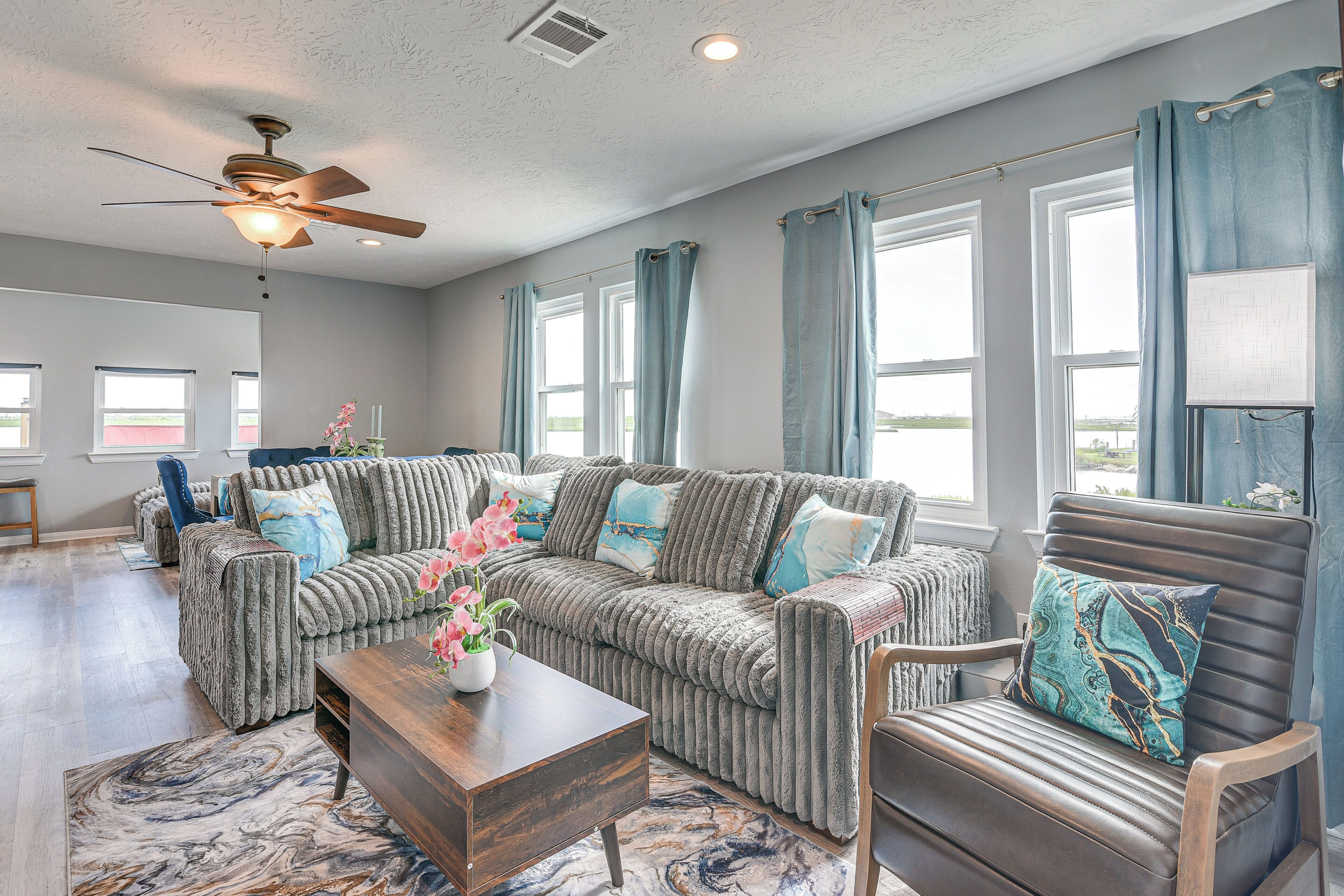 A spacious living room with a sectional sofa, a wooden coffee table, and a ceiling fan.
