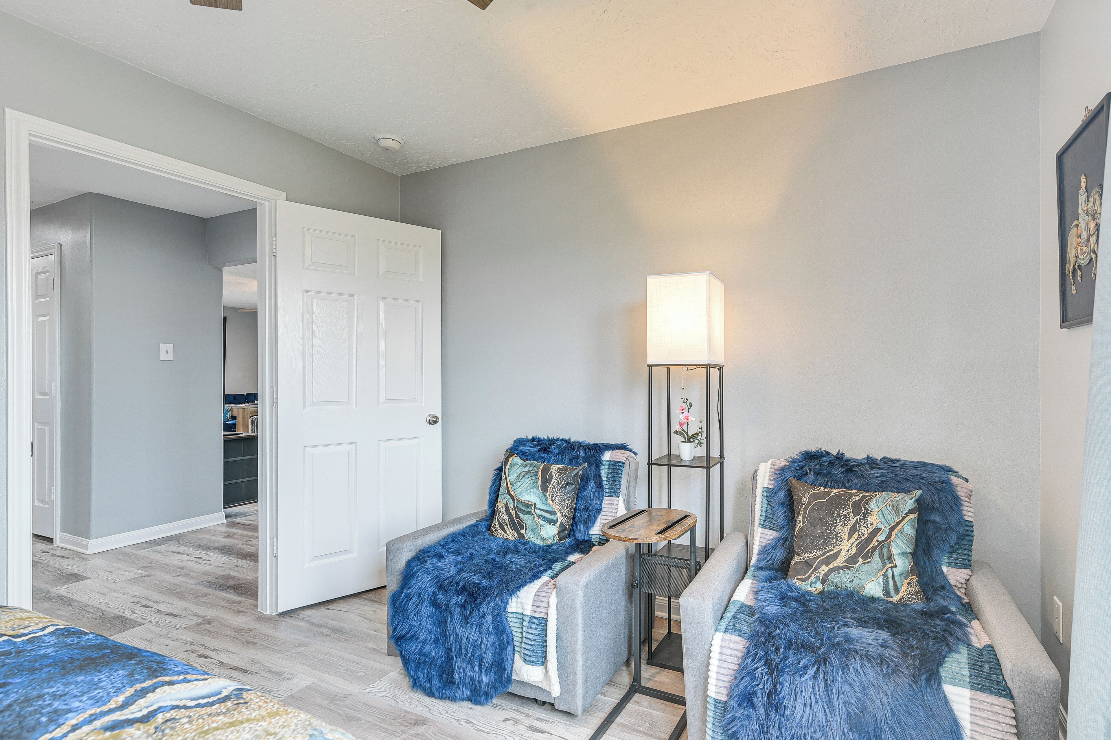 A room with two armchairs, a small table, a lamp, and a door leading to another room.