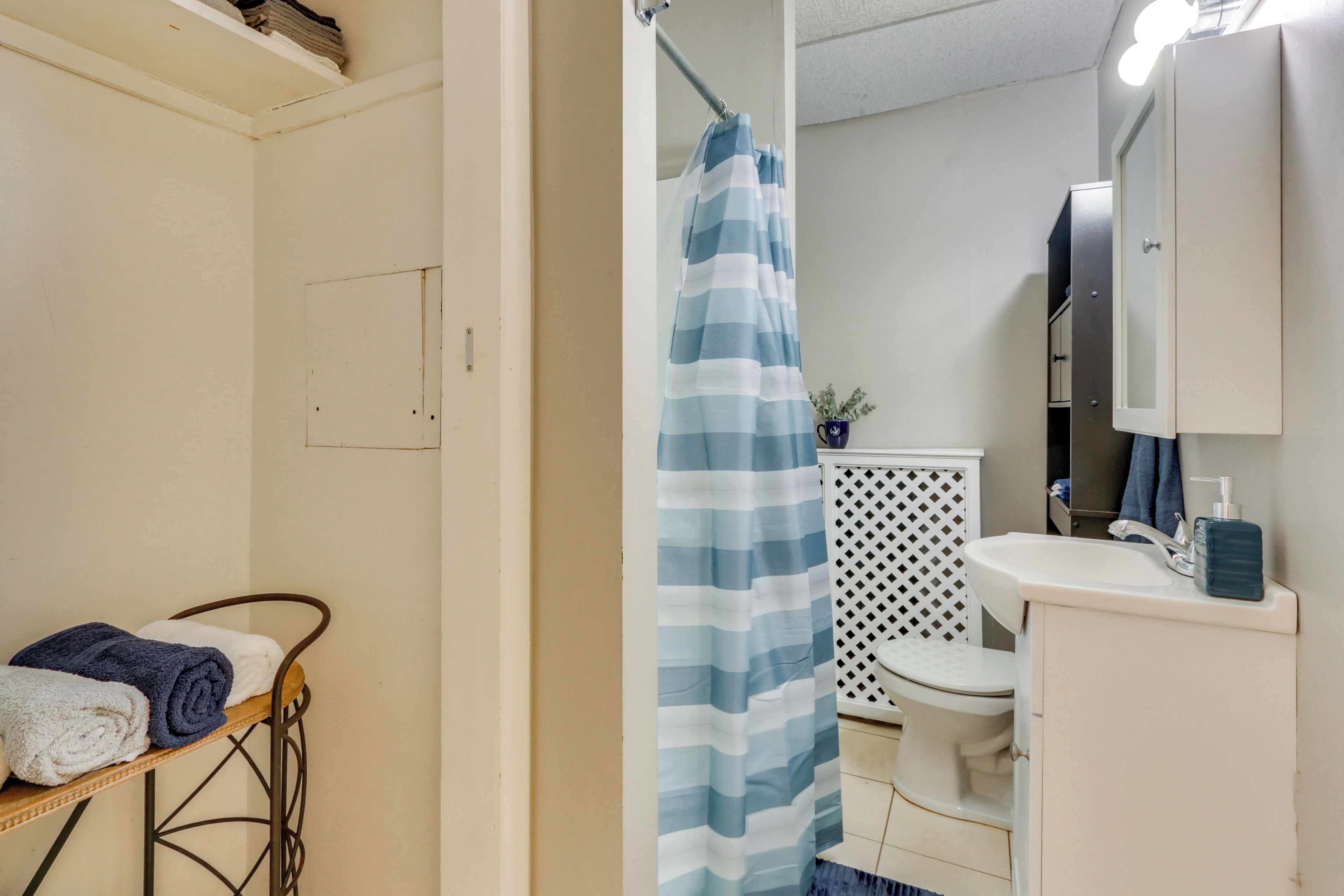 A bathroom with a shower curtain, a toilet, a sink, and a towel rack with towels.