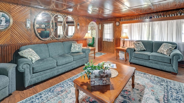 Una sala de estar acogedora con dos sofás verdes, una mesa de centro de madera y una alfombra estampada.