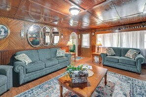 A cozy living room with two green sofas, a wooden coffee table, and a patterned rug. - Hike & Fish: Rustic, Timeless Mckee Home w/ Yard (McKee)