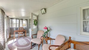 Una habitación con cama de madera, dos sillas, una mesa y un ventanal con cortinas.