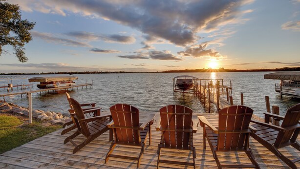 A wooden dock with Adirondack chairs and a boat docked at sunset. - Game Room + Views: Family Retreat on Silver Lake (Lake Park)