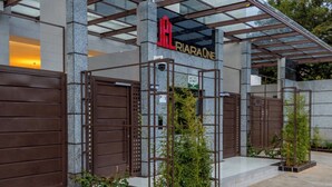 Entrada de hotel con diseño moderno, que presenta fachada de vidrio, portones de metal y un letrero que indica 'LATTICE SECURITY'.