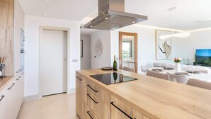 Et moderne køkken med en central ø, et spiseområde med et hvidt borddække og et stort vindue.