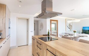 Una cucina moderna con isola centrale, zona pranzo con tavolo bianco apparecchiata e una grande finestra.