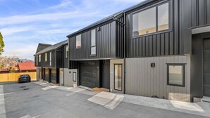 A modern two-story residential building with large windows and a garage. - Central Escape - A modern townhouse with mountain and lake views in the heart of Queenstown. (Queenstown)