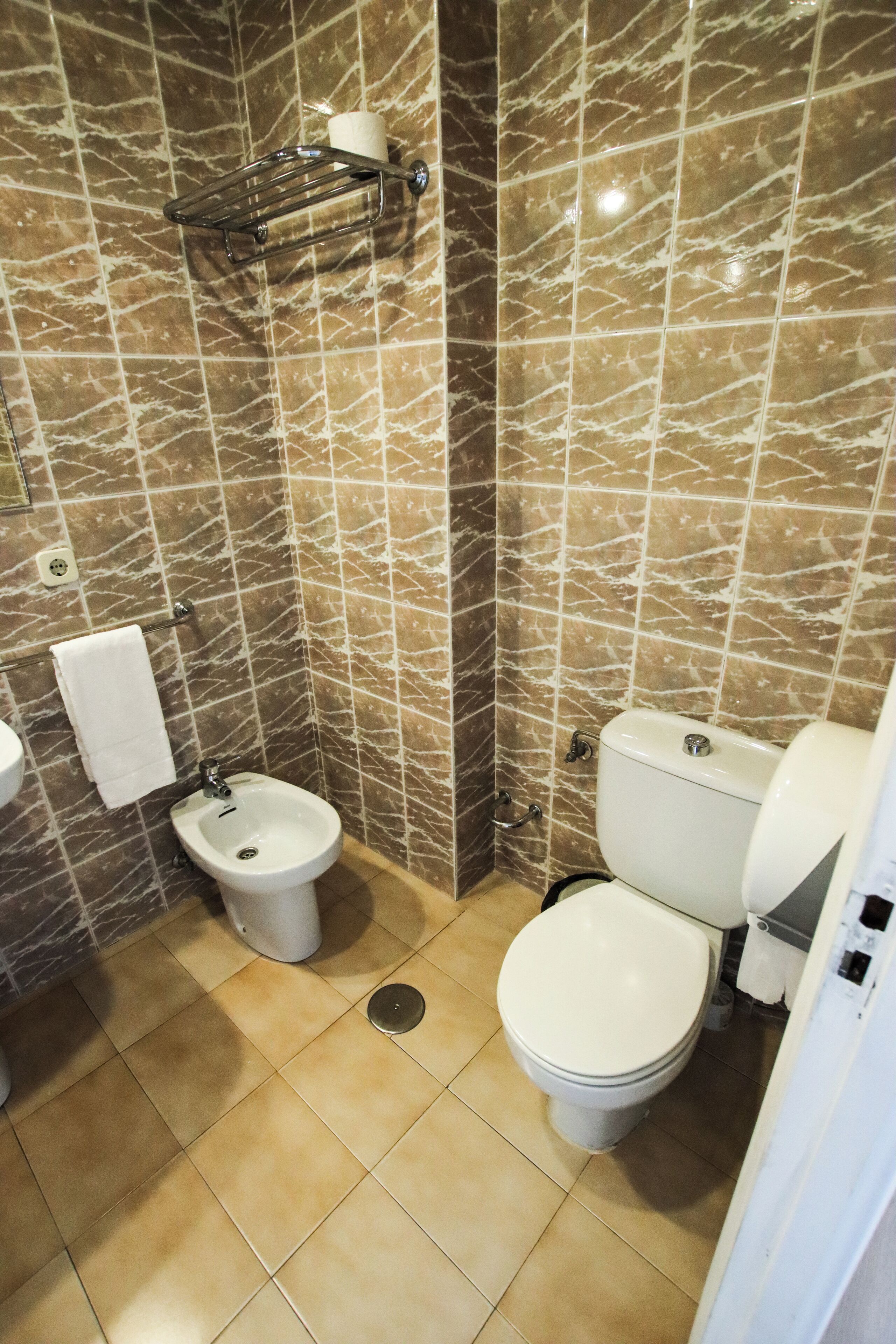Casa de banho com bidé, sanita e um porta-toalhas.