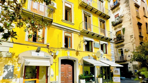 Un edificio amarillo con varios balcones y una entrada a nivel de calle.