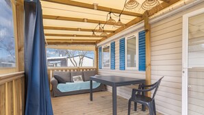 Eine überdachte Terrasse mit Tisch, Stühlen und einer Sitzecke, mit Blick auf die Umgebung.