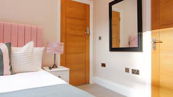 A bedroom with a bed, nightstand, dresser, and a mirror on the wall.