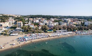 A coastal town with a beach lined with umbrellas and sun loungers.