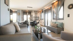 Un salon moderne avec un canapé, une table basse et, au fond, un coin repas.