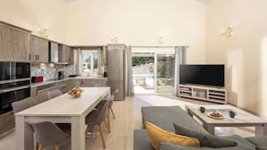 Een moderne keuken met een eethoek, een woonkamer met een bank en salontafel, en een televisie.