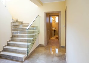 Eine Treppe mit Glasgeländern, die zu einem Badezimmer mit Waschbecken und Spiegel führt.