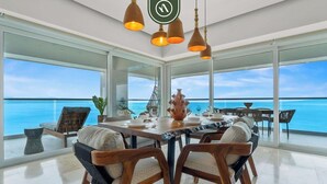 Ein Essbereich mit großem Tisch, Stühlen und Blick aufs Meer.
