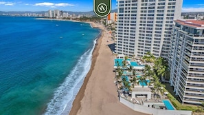 A beachfront hotel with a pool, beach access, and high-rise buildings in the background.