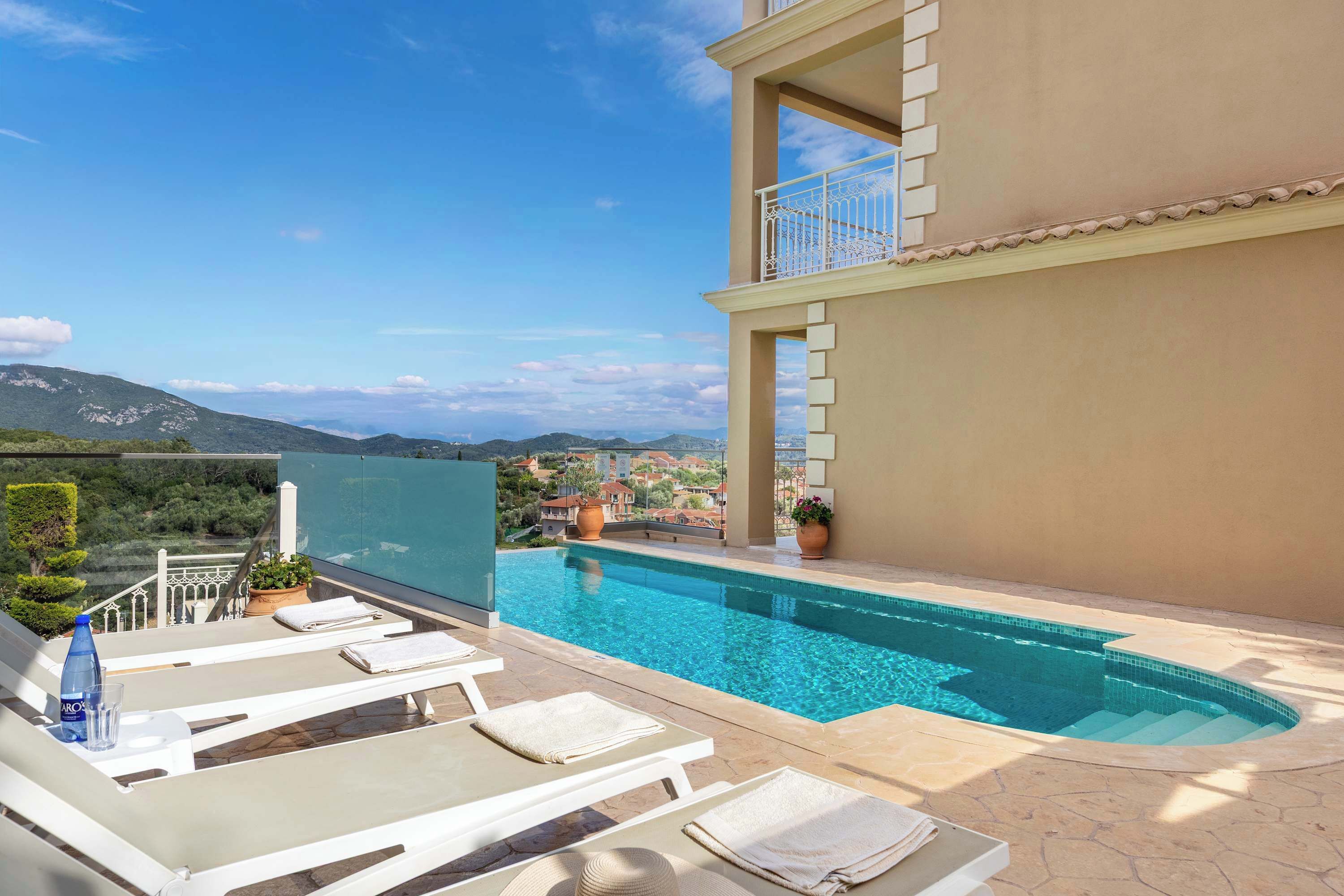A rooftop pool with white lounge chairs and a clear view of the surrounding landscape.
