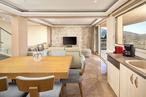 Un salon moderne comprenant un canapé, un téléviseur et un coin repas avec une table et des chaises.