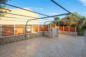Un espace extérieur aménagé avec un revêtement de pavés, un coin salon abrité, des murs en pierre et une clôture en bois.