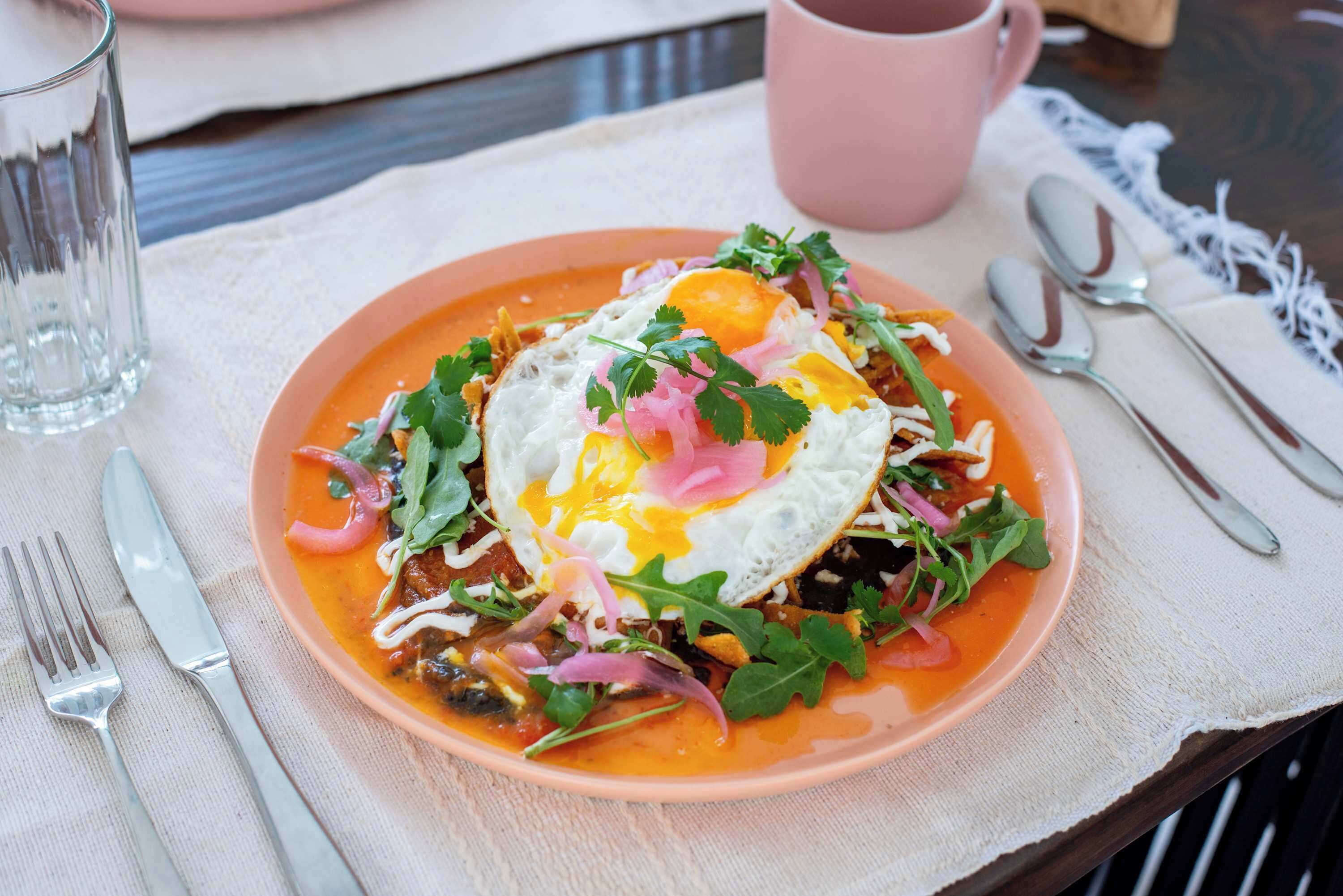 A plate of food with a fried egg, greens, and a pink sauce.