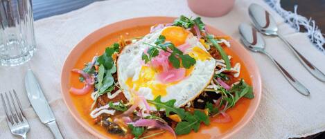 A plate of food with a fried egg, greens, and a pink sauce.