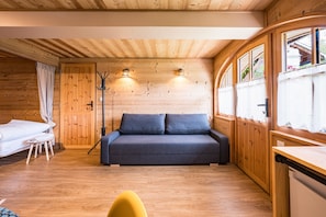 A wooden cabin interior with a bed, sofa, and a small table.