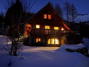 Una cabaña de madera con varias ventanas y un balcón, rodeada de nieve.