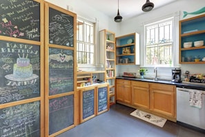 Eine Küche mit Holzausstattung, einer Tafel mit Geburtstagswünschen und einem Fenster mit Meeresstern-Dekorationen.