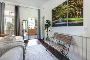 A bedroom with a bed, a bench, and a painting of a forest scene.