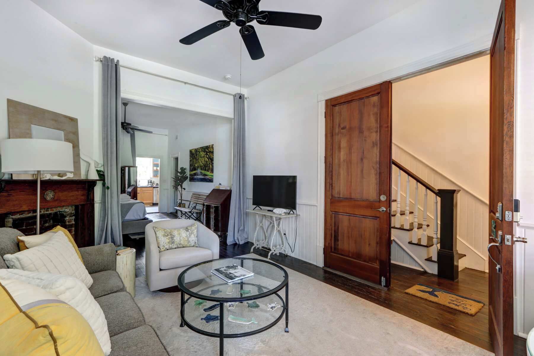 Una sala de estar con sofá, sillón, mesa de centro, televisor y una puerta de madera que da a una escalera.