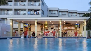 Un hotel con zona de piscina, mobiliario exterior y restaurante frente a la playa.