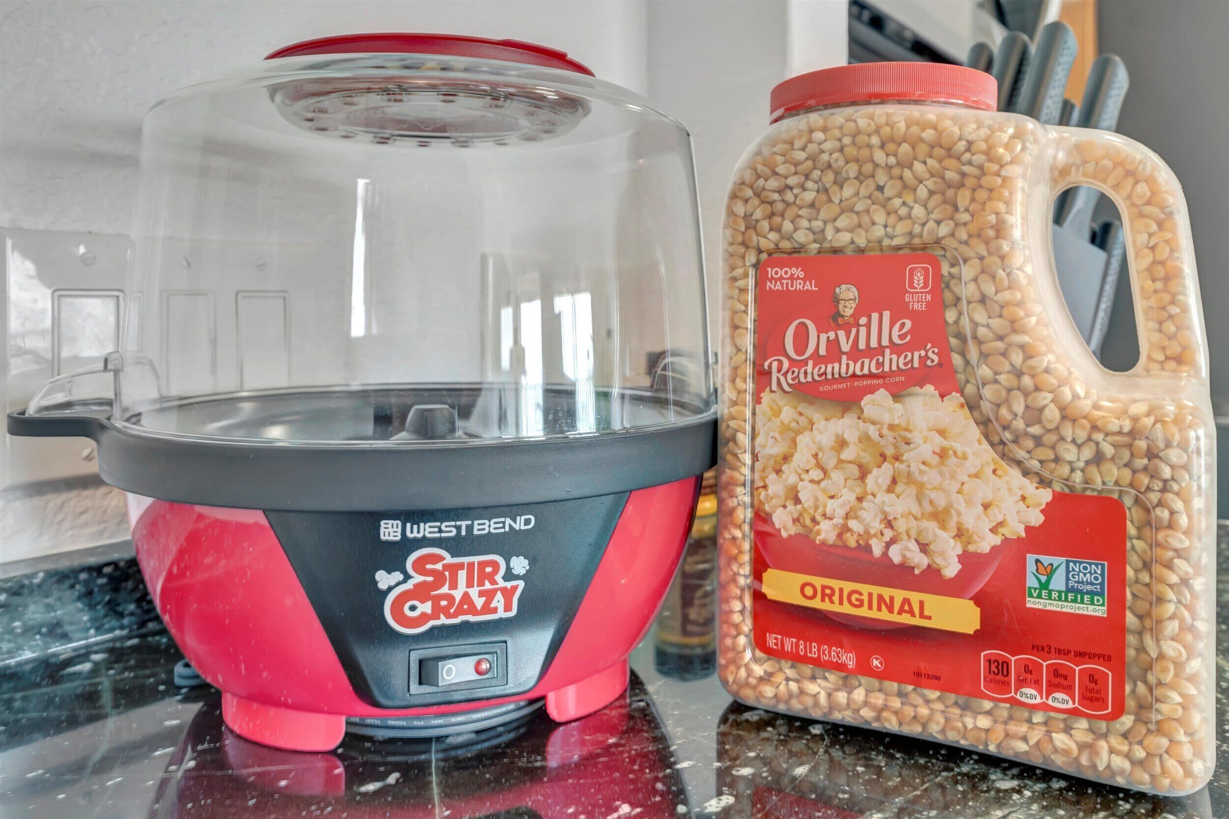 Ett kök med en röd och svart långsamkokare och en burk med Orville Redenbachers klassiska popcorn.